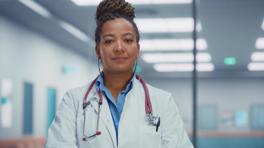 Medical Hospital Medium Portrait: Friendly African American Female Medical Doctor Crosses Hands, Looks at Camera and Smiles. Successful Black Health Care Physician in White Lab Coat Royalty-Free Stock Footage #1085128688