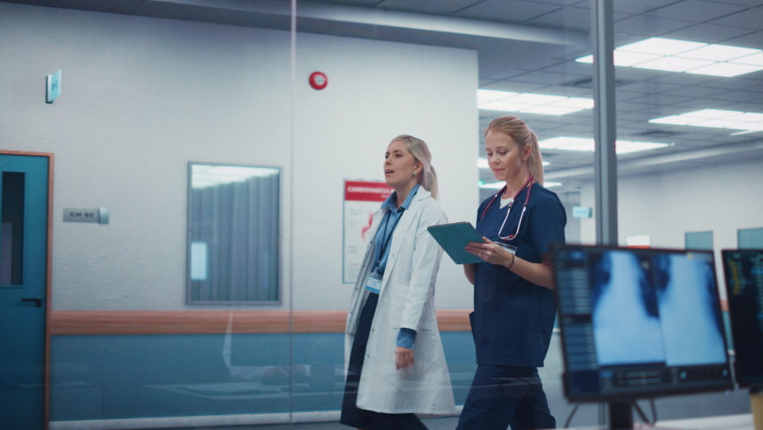 Busy Medical Hospital. Camera Moves From Physician Looking at X-ray on Computer Screen to Nurse and Doctor Walking Through Hallway. Health Care Clinic with Professionals. Cinematic Pan Shot
