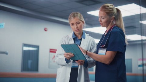 Health Care Medical Hospital. Professional Nurse and Doctor Walking Through Hallway, Talking, Use Digital Tablet Computer, Discuss' Patient Treatment, Drugs or Therapy. Cinematic Slow Motion Pan Shot