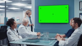 Hospital Conference Meeting Room: Female Doctor Presents Chroma Key Green Screen TV to a Team of Medical Professional. Research Scientists Discuss Patient Treatment, Drugs and Medicine Development