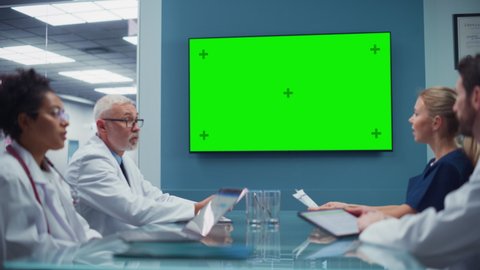 Hospital Conference Meeting Room with Diverse Team of Medical Doctors Looking at Chroma Key Green Screen and Talk. Health Care Medical Experts Develop New Drugs, Medicine, Patient Treatment Method