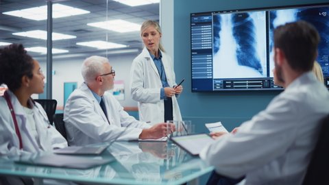Health Care Research Hospital Meeting Room: Female Physician Presents Patient X-ray on TV Screen, Team of Medical Doctors Discuss Treatment. Research Scientists Talk of Course of Cure, Drugs, Medicine