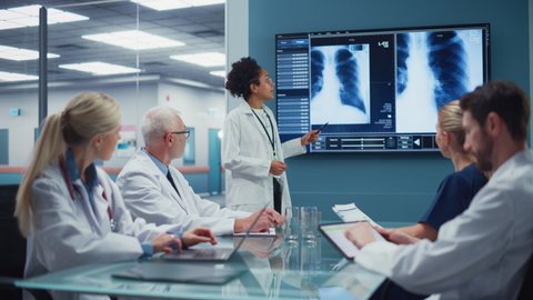 Hospital Conference Meeting Room: Young Promising Black Female Physician Presents Patient X-ray on TV Screen, Team of Doctors Discuss Treatment. Research Scientists and Drug, Medicine Development