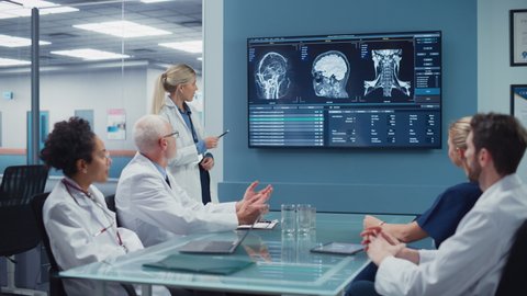 Hospital Conference Meeting Room: Neurologist Shows MRI scan, Magnetic Resonance Image on TV Screen, Team of Neuroscientists, Doctors Discuss Patient Treatment, Drug Research, Medicine Development
