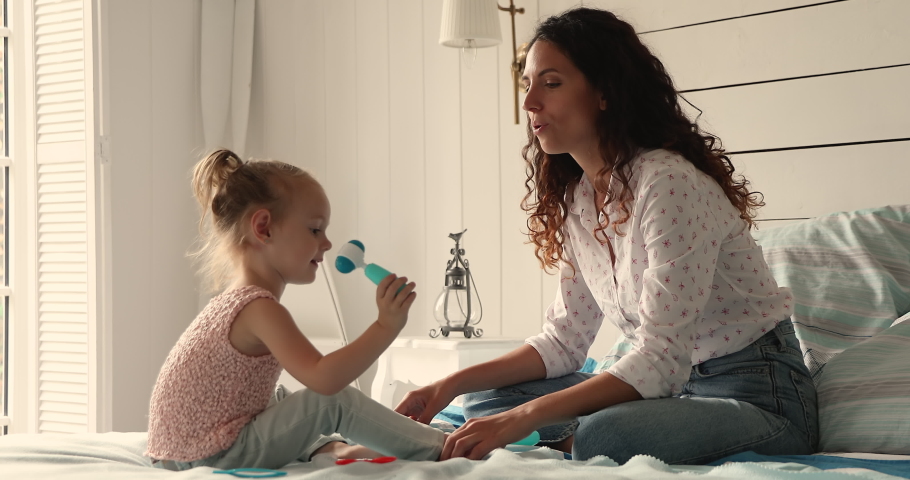 Little 4s daughter plays therapist, holds medical equipment plastic toys, heals her mum, makes health check up, hearing test use playthings sit on bed at home. Future profession, vocation, fun concept Royalty-Free Stock Footage #1085132246