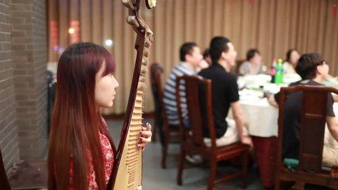 Nanjing,China-July,2105: a beautiful female artist playing Pipa (chinese traditional lute) in the dinner