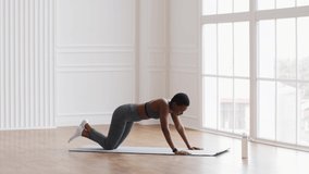 Fitness Training. Sporty Black Female Doing Knee Push-Up Exercises In Studio, Fit African American Woman In Sportswear Working Out On Yoga Mat In Spacious Room, Side View, Slow Motion Footage