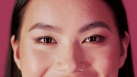 Cropped Shot Of Asian Female Face With Unaltered Skin And Natural Makeup, Closeup Of Smiling Young Korean Woman Eyes Looking At Camera While Posing Over Pink Background, Slow Motion Footage