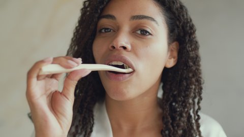 Deep teeth cleaning. Mirror pov portrait of young black lady brushing her teeth with toothbrush, caring about her dental hygiene at home in morning, slow motion