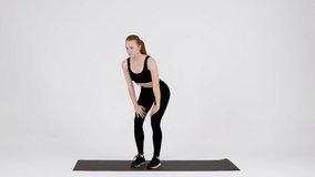Athletic Young Woman Doing Stomach Vacuum Exercise While Training In Studio, Sporty Lady Standing On Fitness Mat Over White Background, Breathing In And Out, Exhaling Air For Flat Belly, Slow Motion