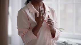 Unrecognizable Black Female Applying Cream Moisturizer On Hand Caring For Skin Standing At Home. Cropped Shot Of Woman Moisturizing Hands. Cropped Shot, Slow Motion