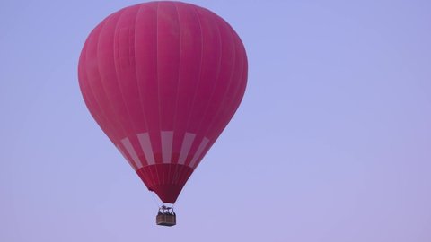 Red hot air balloons basket with tourists flying in the sky.