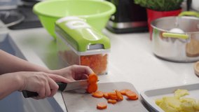 Woman cooking salad in the kitchen using a vegetable chopper with container, chop and slice boiled potatoes and carrot with food slicer on kitchen countertop closeup. High quality 4k footage