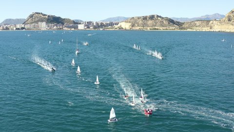 Aerial view of little sailing boats OPTIMIST starting a race, in the coast of Alicante city, Spain.