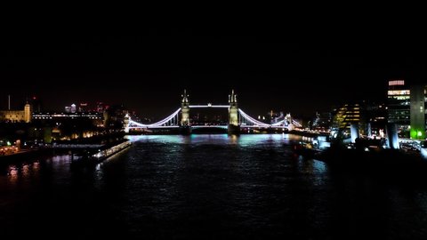 Establishing Aerial drone View of Tower Bridge at night with Canary Wharf in the background by the Thames River, London United Kingdom, UK