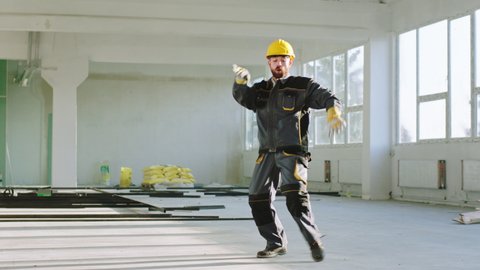 Happy and excited construction worker at construction site dancing and enjoy the moment he wearing uniform and safety helmet