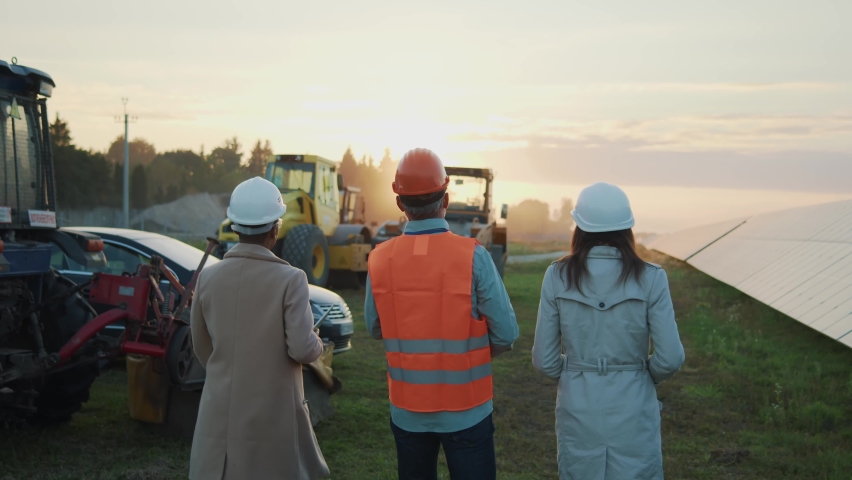 Multi-ethnic group of industrial engineers walking near solar panels discussing building plan. Heavy machinery. Business industry. Ecology station. Royalty-Free Stock Footage #1085151014