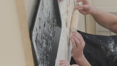 Vertical Video. Family of Three Cooking Cookies Together at Home. Man in Kitchen Apron Rolling Out the Dough with a Rolling Pin while his Wife and Little Daughter Putting Raw Cookies on a Baking Sheet