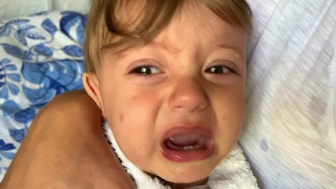 Mother decongesting baby mucus with saline salt water, removing mucus from crying baby