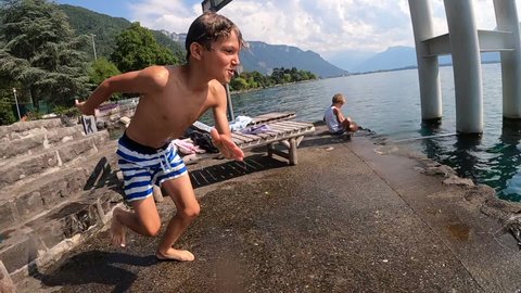 Child running and jumping in lake water. Young boy splashing inside fresh water