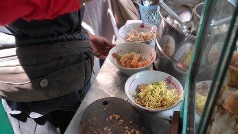 Yogyakarta, Indonesia - December 11, 2021: A person mixes a meatball menu which is served hot with clear beef broth, mixed with noodles, vermicelli and tofu.