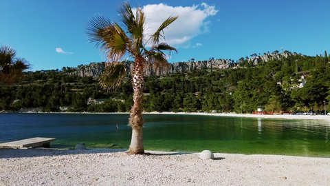 Handheld panning shot of Kasjuni beach in Split, Dalmatia region in Croatia. Scenic landscape with a pine tree in the foreground. Traveling during the Corona Pandemic. Also known as Kasuni Beach 4K