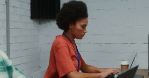 A young man of European appearance beckons a young African American woman working nearby to his laptop to discuss a work issue. 4K video, red komodo