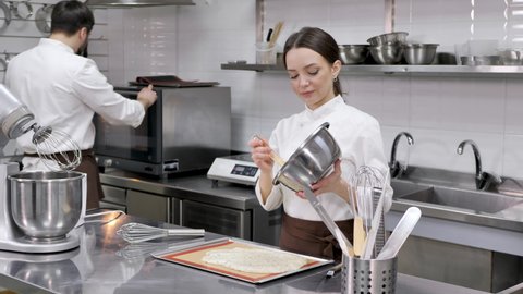 Pastry chef woman pours the dough on a baking sheet with parchment.