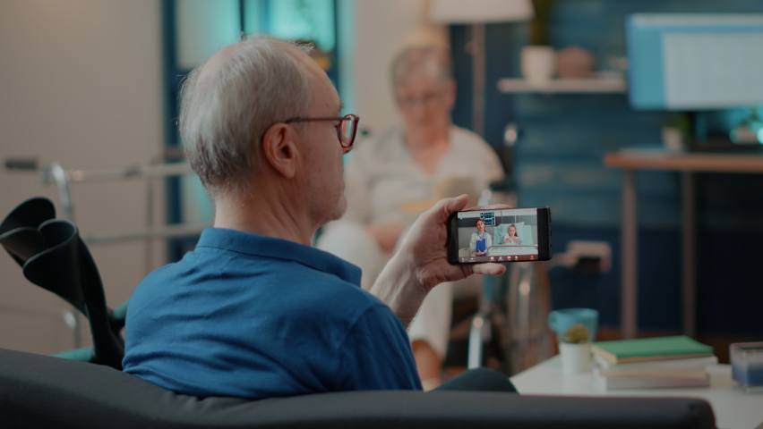 Senior man attending online meeting on smartphone, chatting with doctor and child in hospital. Elder person using remote videoconference call for telehealth conversation on mobile phone. Royalty-Free Stock Footage #1085169674