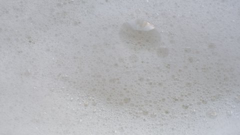 Close-up shooting soapy water. Foam abstract background. Soap foam popping isolated. Texture of white soap foam with bathtub bubbles. slow video