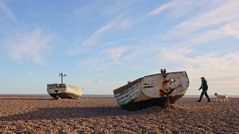 Aldeburgh, Suffolk. UK. January 2nd 2022. Tourists with a dog walking past the old fishing boats on Aldeburgh beach.