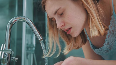 Woman in bathroom. Young beautiful blonde girl in lingerie washing face cleansing with water enjoying skincare routine. Female beauty treatments. Healthy lifestyle.
