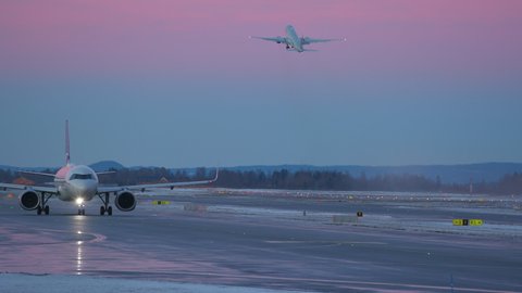 Oslo Airport Norway - December 16 2021: airplane airbus a320 neo taxiing at night very peri pantone sky colors another distant aircraft take off