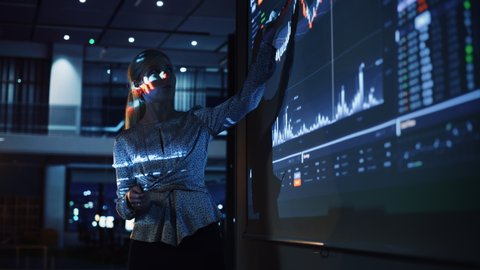 Business Conference Meeting Presentation: Businesswoman does Financial Analysis talks to Group of Businessspeople. Projector Screen Shows Stock Market Data, Investment Strategy, Revenue Growth