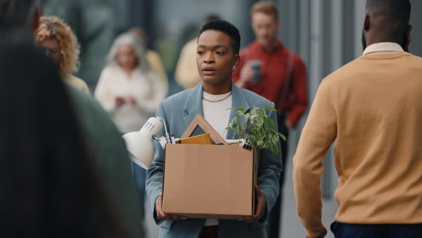 African american woman in formal clothes walking on crowded city street with box full of office stuff in hands. Concept of people, relocation and occupation. Royalty-Free Stock Footage #1085185283