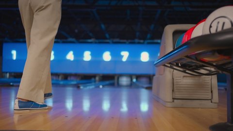 The camera follows one woman throwing a bowling ball on the playing track and jumping around rejoicing in the downed pins. One man bowling in slow motion
