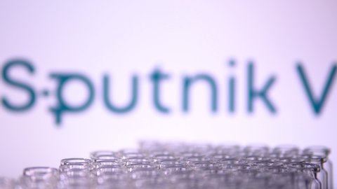 Toronto, Ontario, Canada - February 14, 2021 : Sputnik V name in blur and vaccine vials moving containing Gam-COVID-Vac. Russian Covid-19 vaccine concept. Moving shallow depth of field.