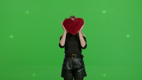 Happy caucasian girl with a hand-made paper heart in her hands expresses delight and joy , demonstrating love care on green screen background. Valentine's Day