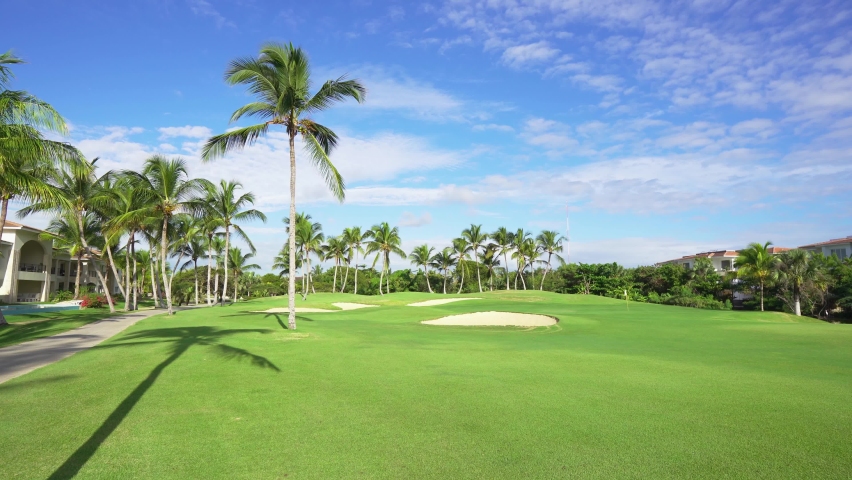 Beautiful green golf course at the golf club. Palm trees on a green grass background. Summer park on a sunny morning under the blue sky. Royalty-Free Stock Footage #1085196470