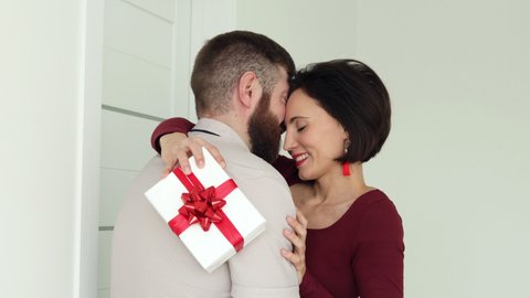 Husband hugs wife makes surprise. Close up face happy female cuddles beloved man hold giftbox express gratitude for gift at 8-march International Women Day, Valentines Day