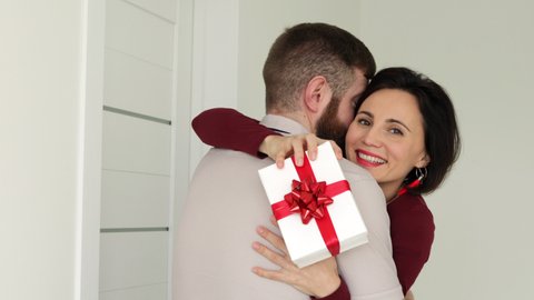 Husband hugs wife makes surprise. Close up face happy female cuddles beloved man hold giftbox express gratitude for gift at 8-march International Women Day, Valentines Day