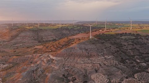 Aerial view of a wind farm on clay strata of different colors filmed by drone in spring during sunset in Guadalajara in Spain.
