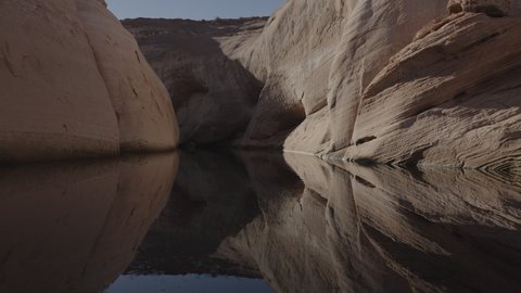 Flyover of canyon lake of reflections of rock formations - Glen Canyon, Utah, United States