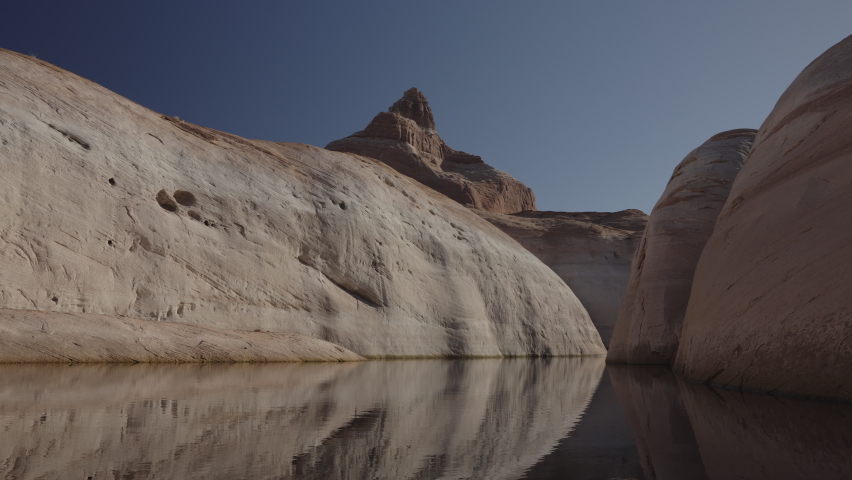 Flyover of canyon lake of reflections of rock formations - Glen Canyon, Utah, United States