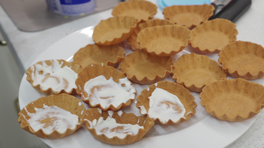Woman cooking festive dinner in the kitchen making canape topped with some savoury food. High quality 4k footage