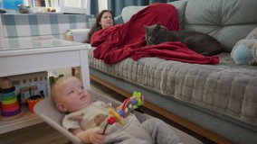 Family watching tv together in the living room, mother with baby and cat are relaxing in the evening. High quality 4k footage