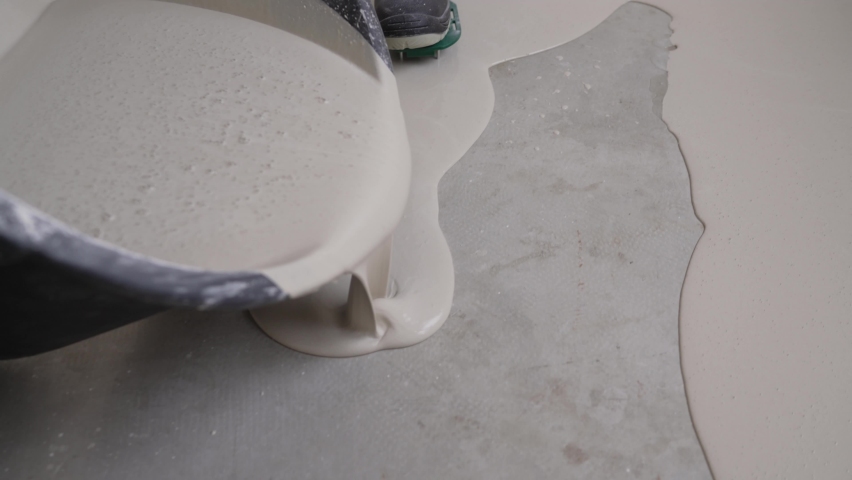 Self-leveling epoxy. Leveling with a mixture of cement floors. Construction workers pour out mortar of cement from bucket. Leveling with a mixture of cement floors. Royalty-Free Stock Footage #1085208170
