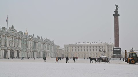 SAINT-PETERSBURG, RUSSIA - JANUARY 09 2022:  Horse-drawn entertainment carriage rides  thru a Palace Square in front of state museum Hermitage and Alexander Column. Heavily snowing