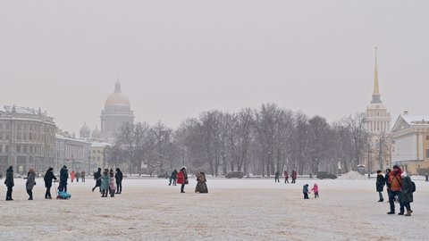 SAINT-PETERSBURG, RUSSIA - JANUARY 09 2022: View at Saint-Isaac's cathedral and Admiralty building from Palace Square. People walking around taking pictures. Snowing heavily that winter day