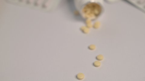 Selective focus. Close up shooting of different pills falling on table with blisters with medicine.Tablets and pills. Close up shooting